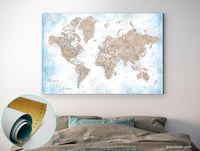 Personalized world map print on rolled canvas, with cities and US state capitals in painterly blue and brown watercolor. "Ghada"